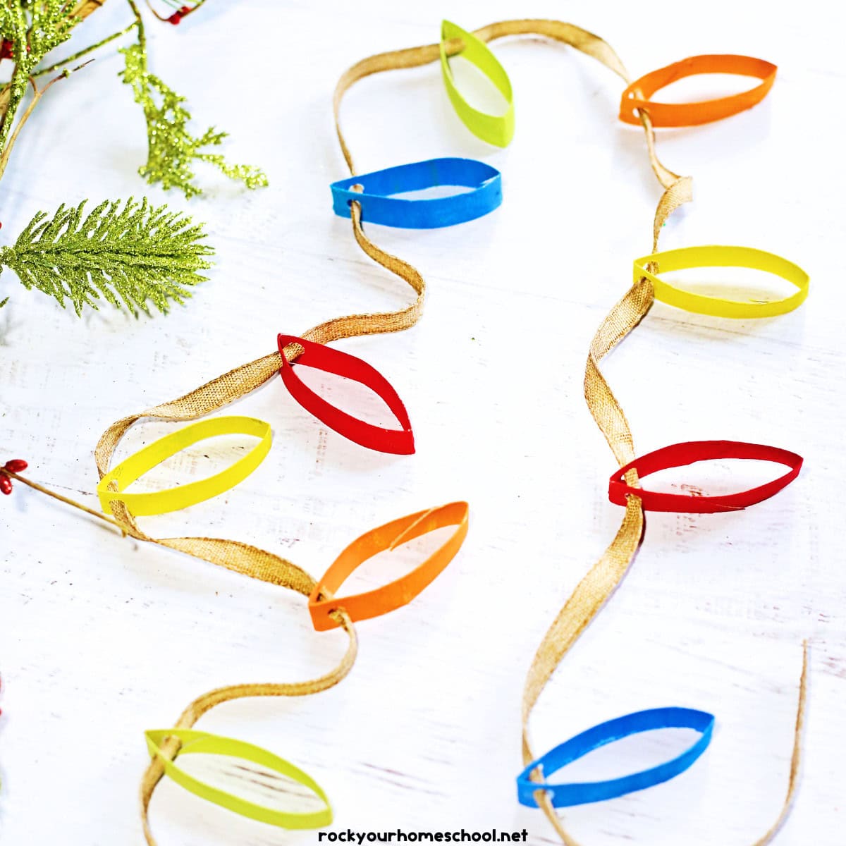 Example of colorful Christmas lights craft made out of toilet paper roll rings, paint, and ribbon.