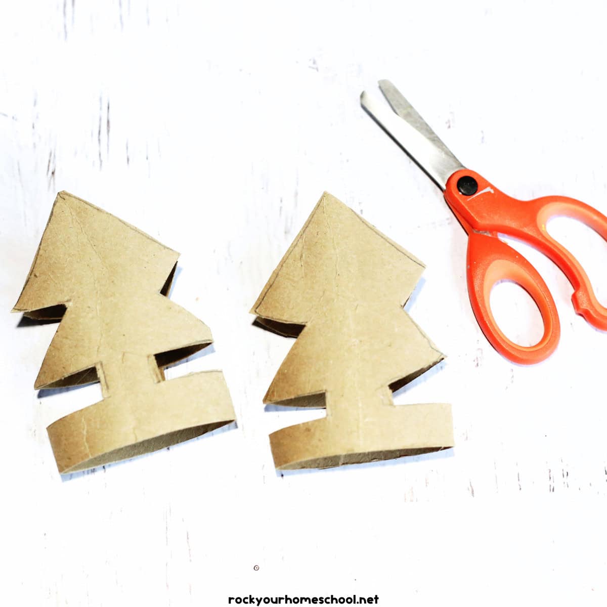 2 toilet paper rolls cut out as Christmas trees with a pair of scissors.