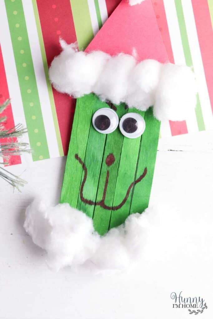 Example of popsicle stick Grinch craft with cotton balls and googly eyes.