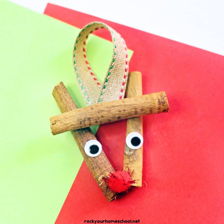 Example of cinnamon stick reindeer ornament craft with googly eyes, red pom pom, and ribbon.