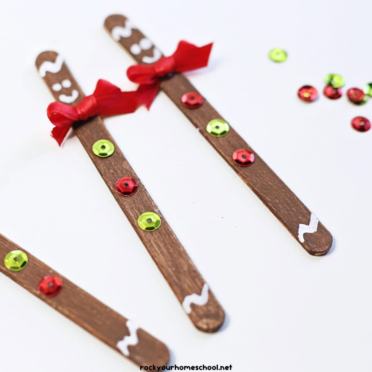 Examples of popsicle stick gingerbread mean with red ribbons and sequins of red and green.