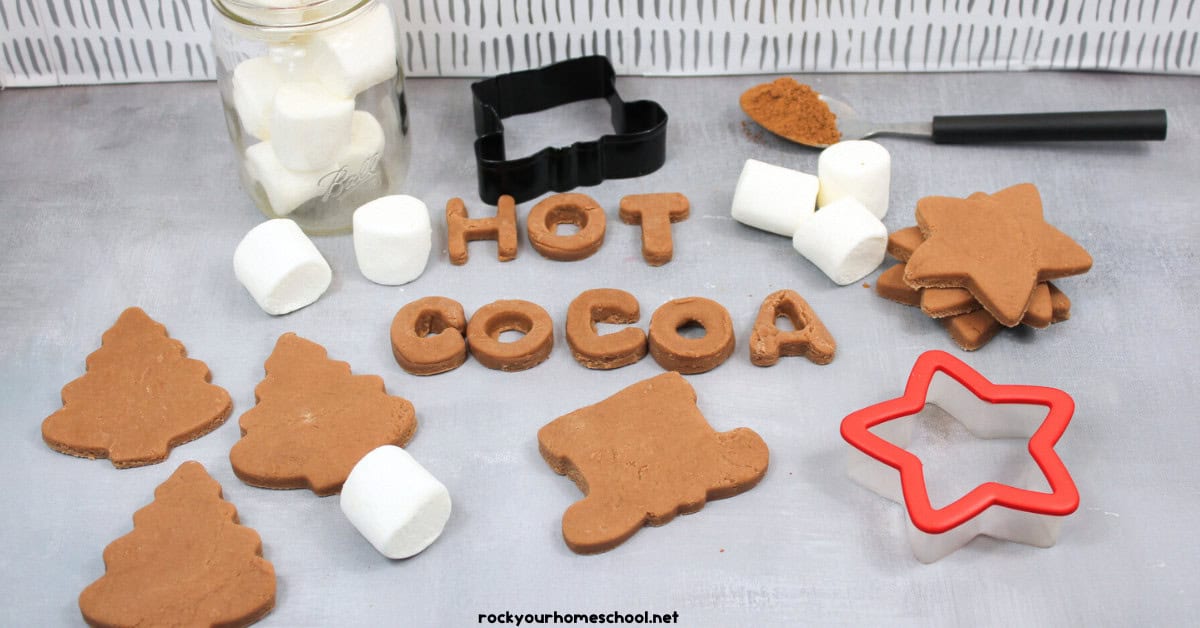 Example of hot chocolate playdough with marshmallows, cookie cutters, and spoon with cocoa powder.