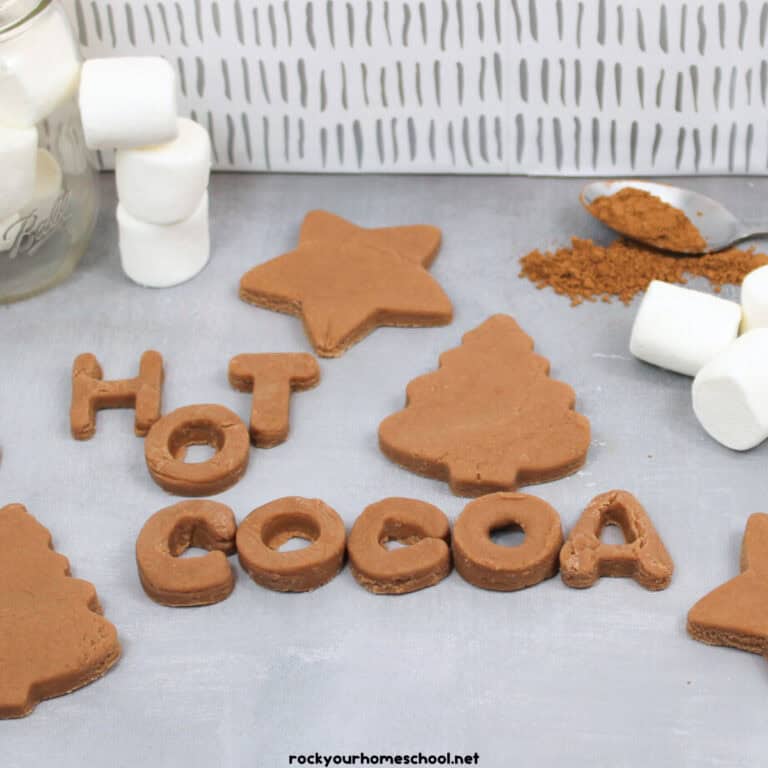 Hot chocolate playdough in star and Christmas tree with marshmallows and cocoa powder on spoon and H O T C O C O A.