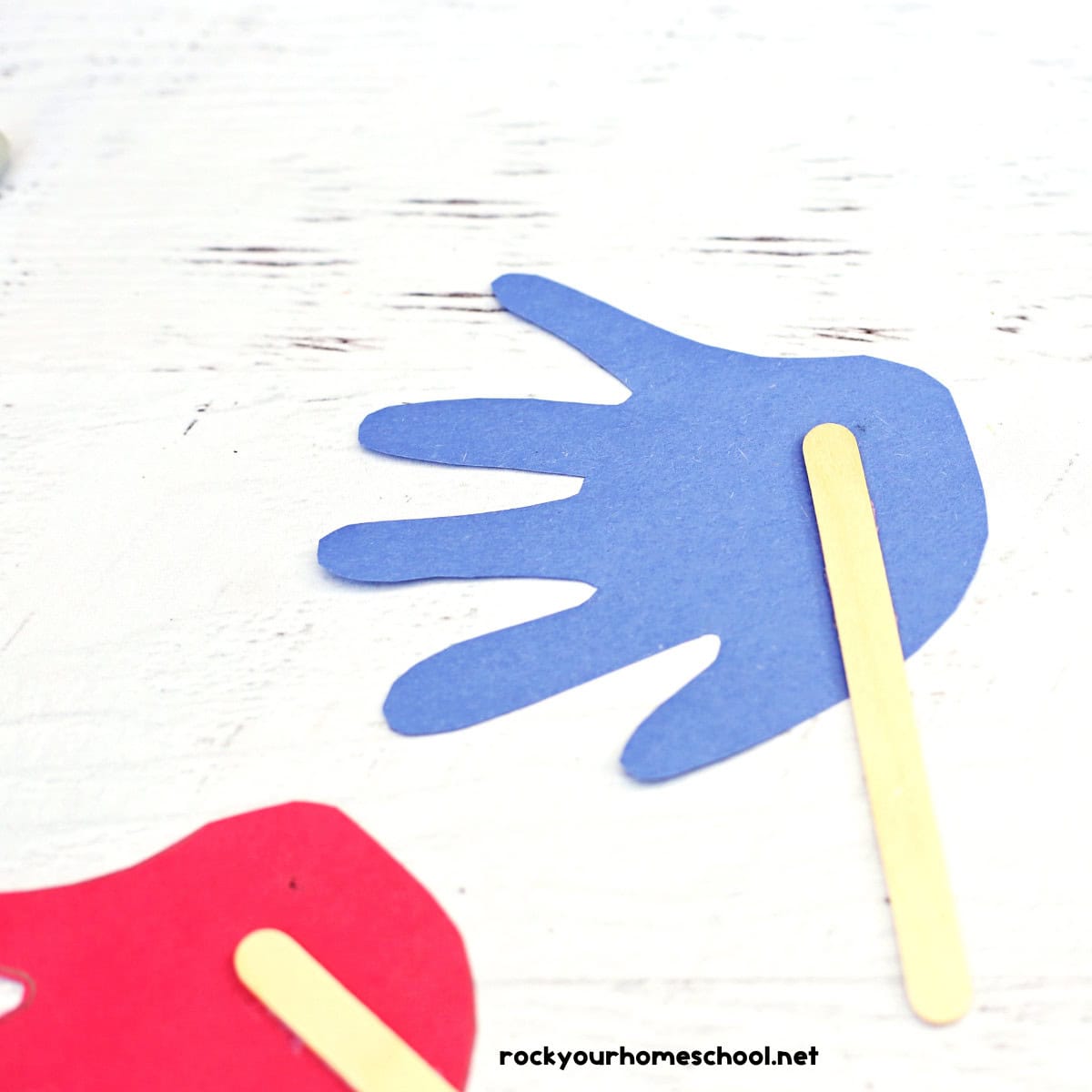 Popsicle stick glue on blue handprint.