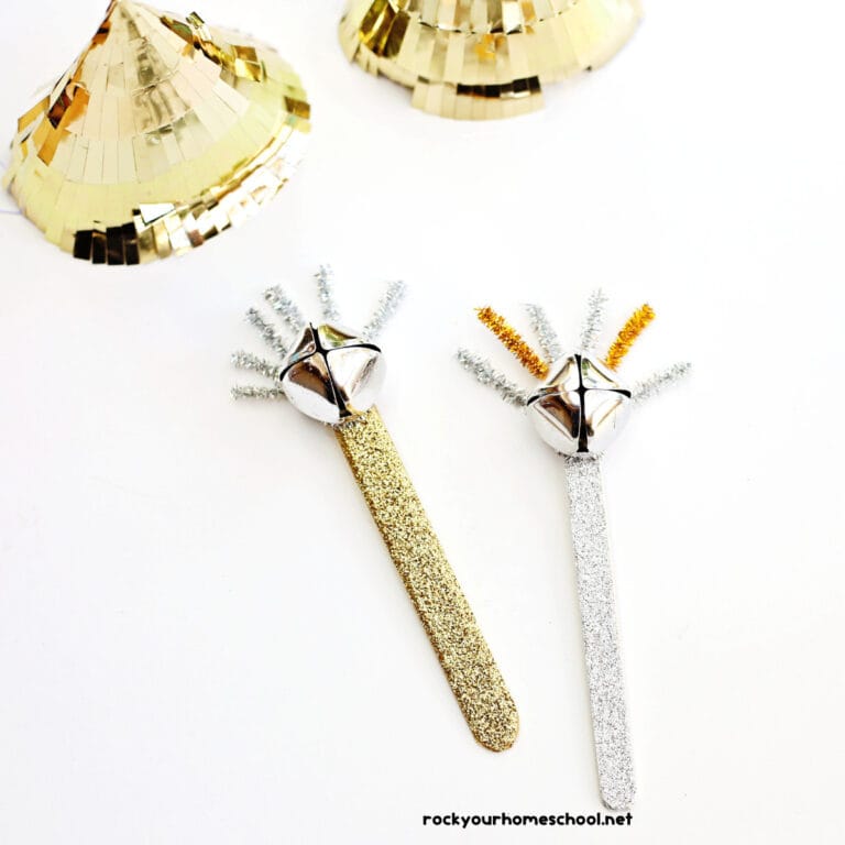 Two examples of popsicle stick noisemaker crafts for kids using gold and silver washi tape, jingle bells, and pipe cleaners.