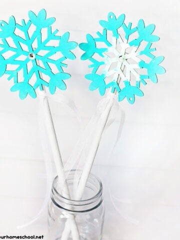 Two snowflake wand crafts in light blue and white in glass jar.