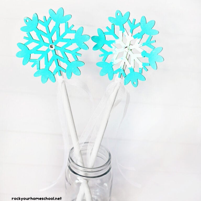 Two snowflake wand crafts in light blue and white in glass jar.