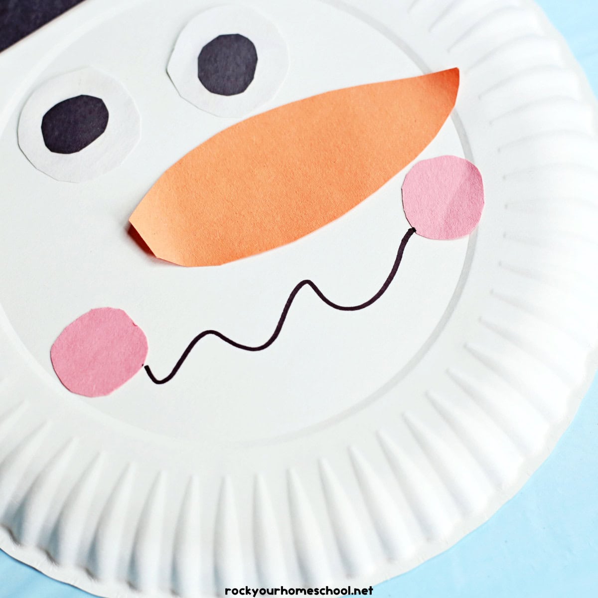 Paper plate craft with construction paper pieces with black marker squiggly line smile.