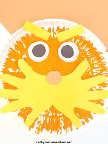 Example of The Lorax paper plate craft made with fork painting and paper handprints.