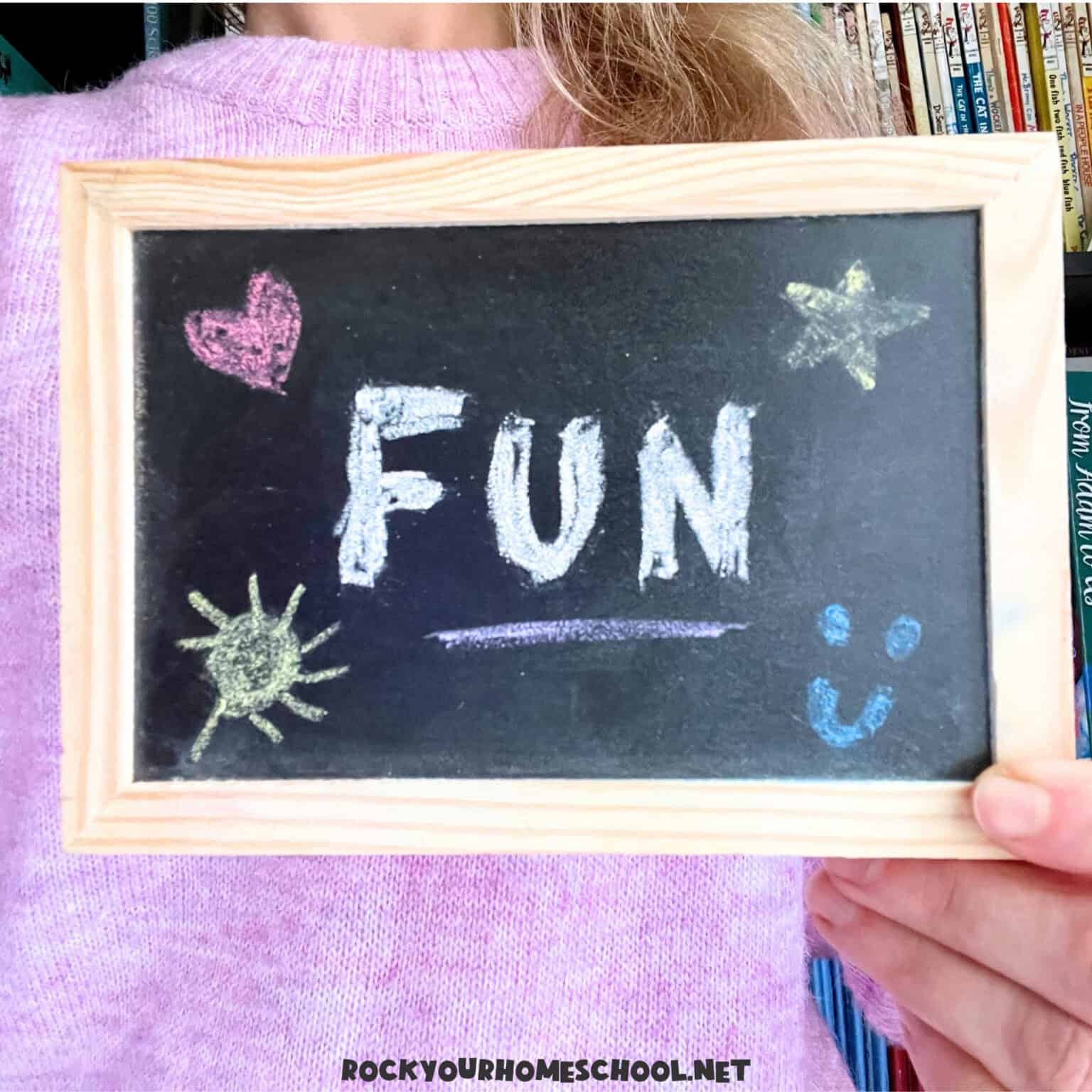 Woman holding black chalkboard with the word FUN on how to make homeschool fun.