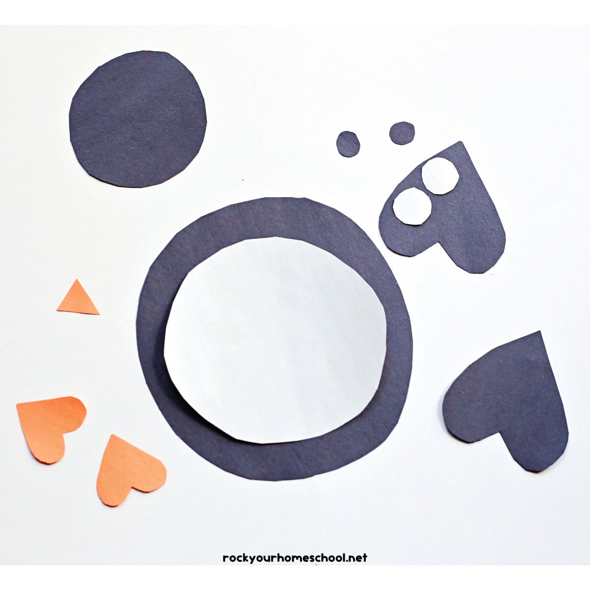 Cut out shapes of black, white, and orange construction paper.