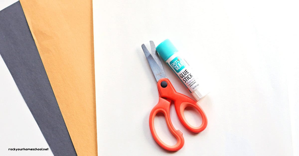 Black, orange, and white construction paper with child scissors and glue stick.