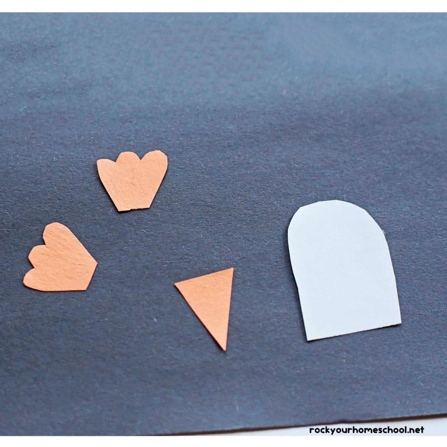 White and orange pieces of construction paper on black construction paper.