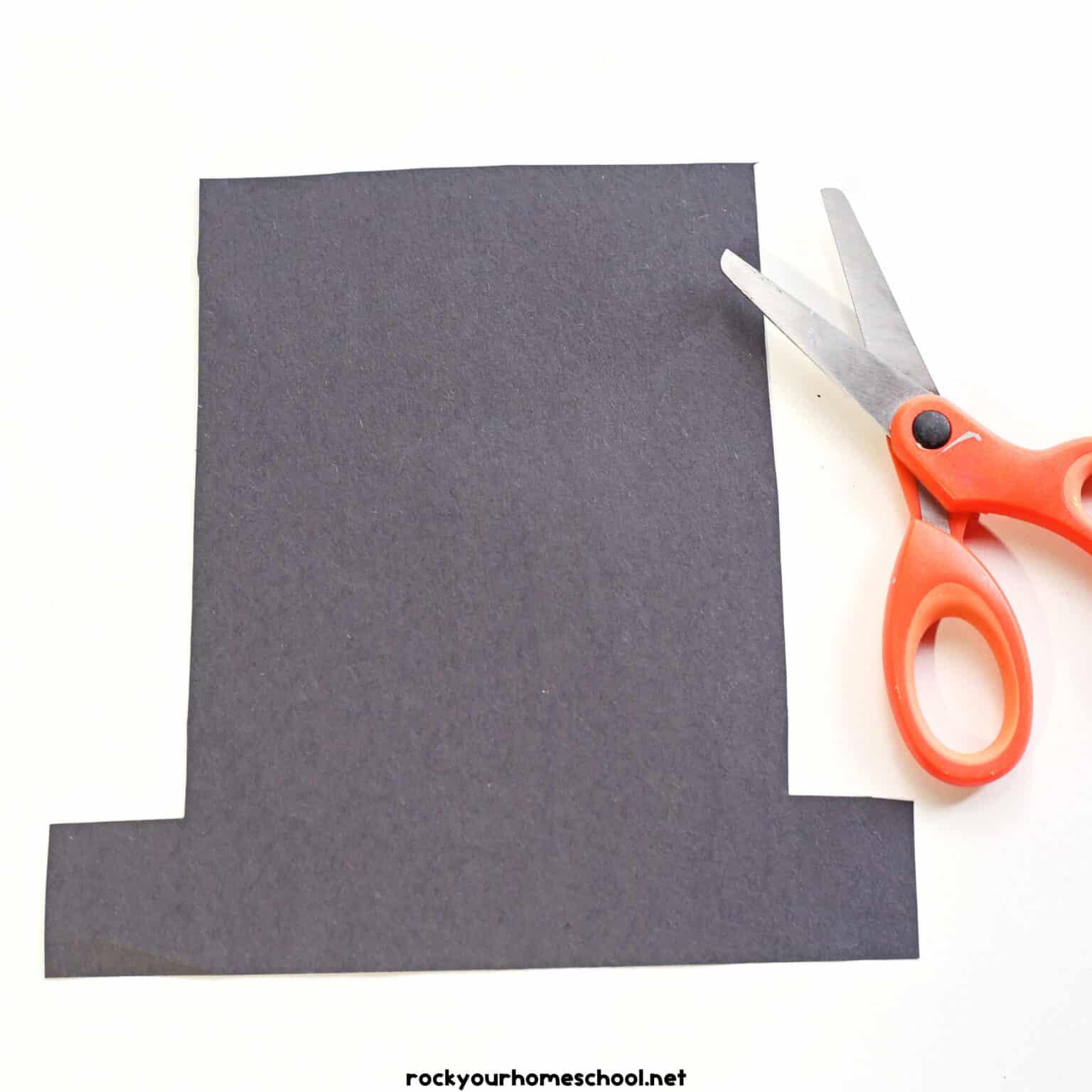 Black construction paper hat shape with scissors.