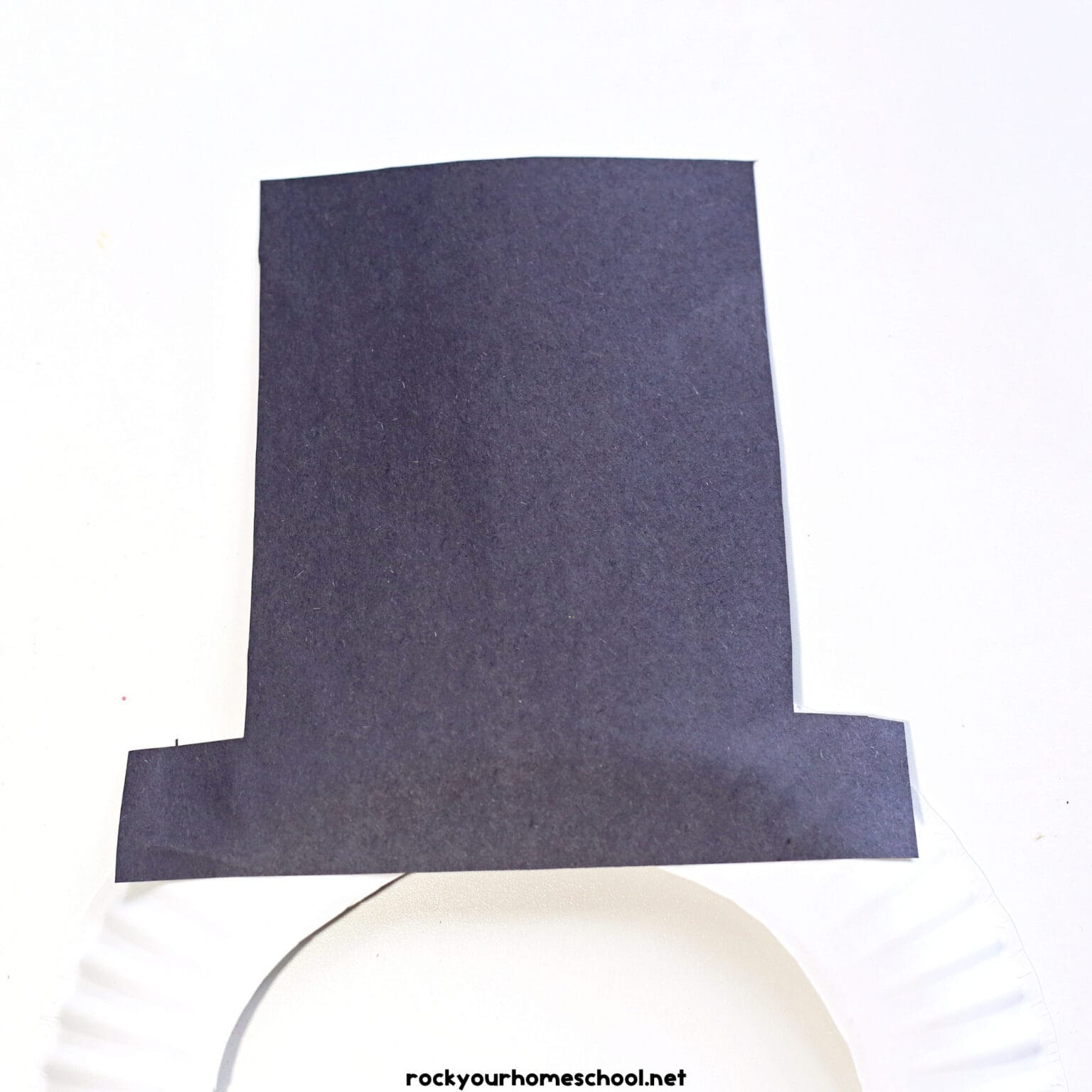 Black construction paper hat on paper plate.