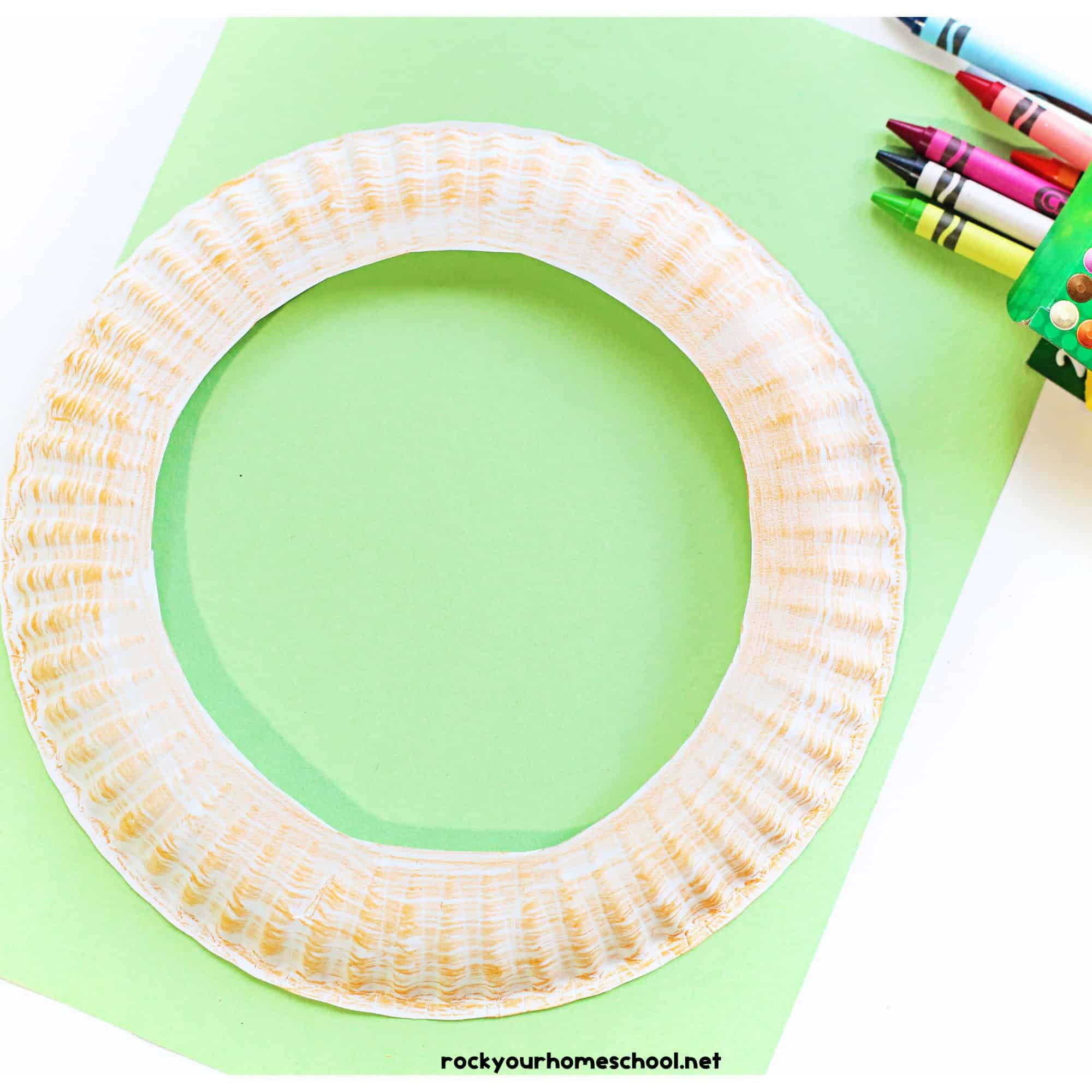 Paper plate with center cut out and lightly colored brown with crayons.