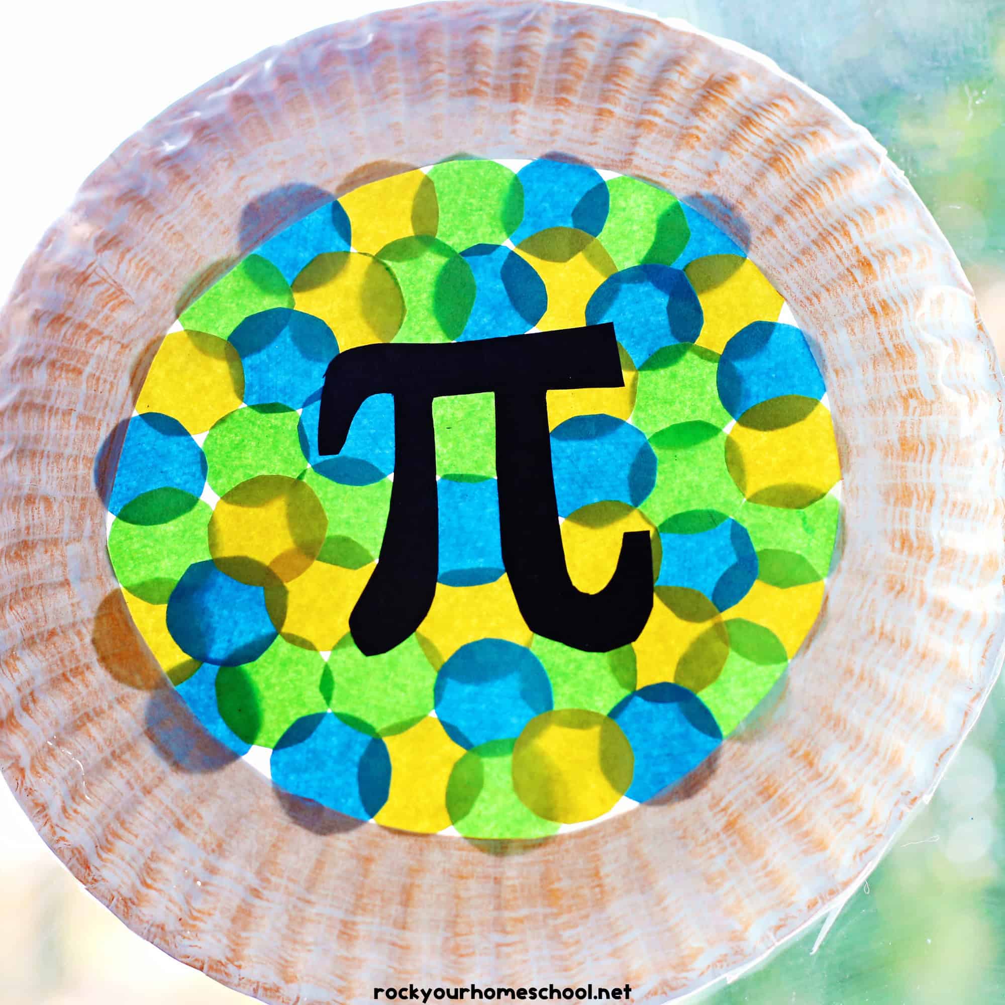 Example of Pi Day craft made with a paper plate and yellow, blue, and green circles of paper for a colorful suncatcher.