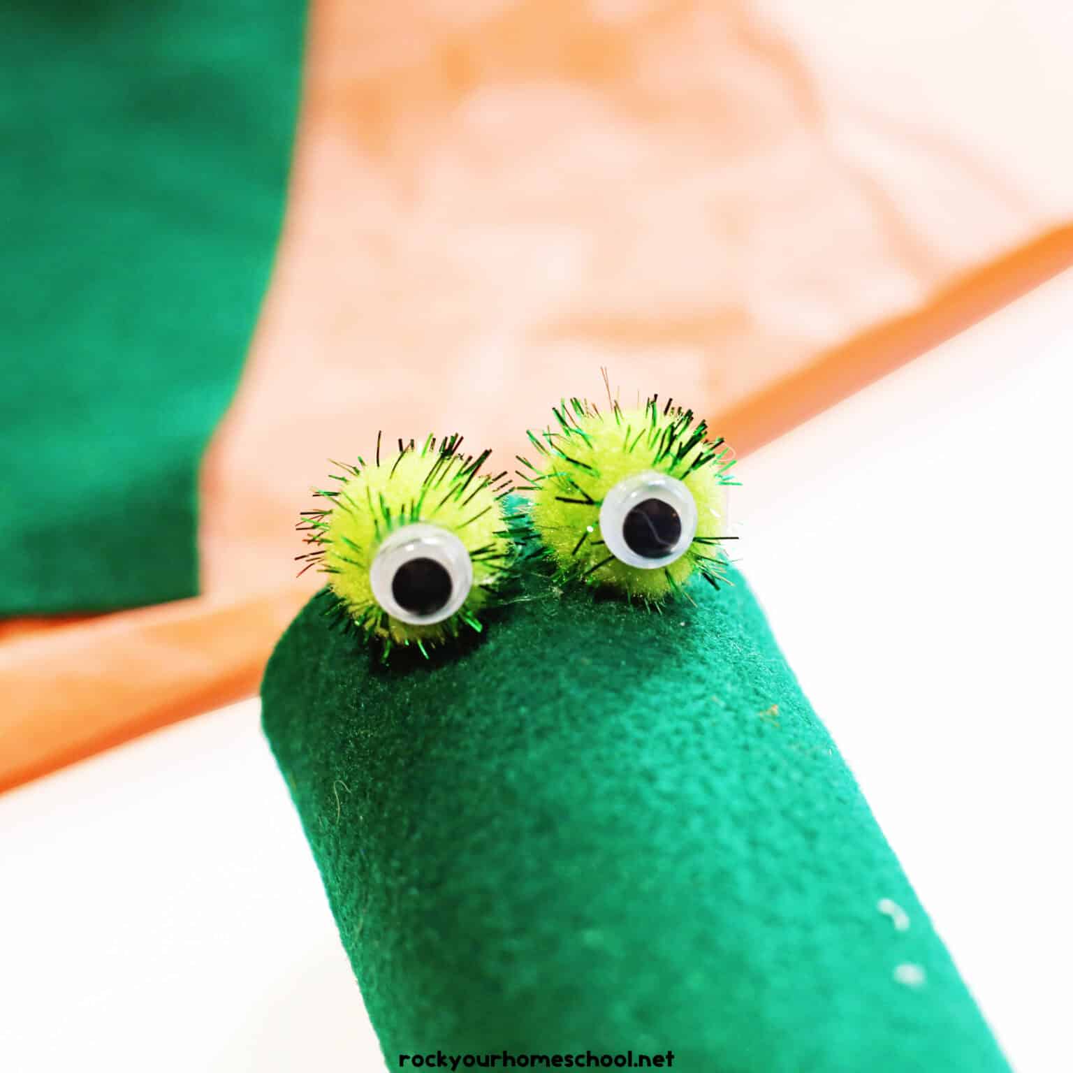 2 light green pom poms with googly eyes glued onto green felt.