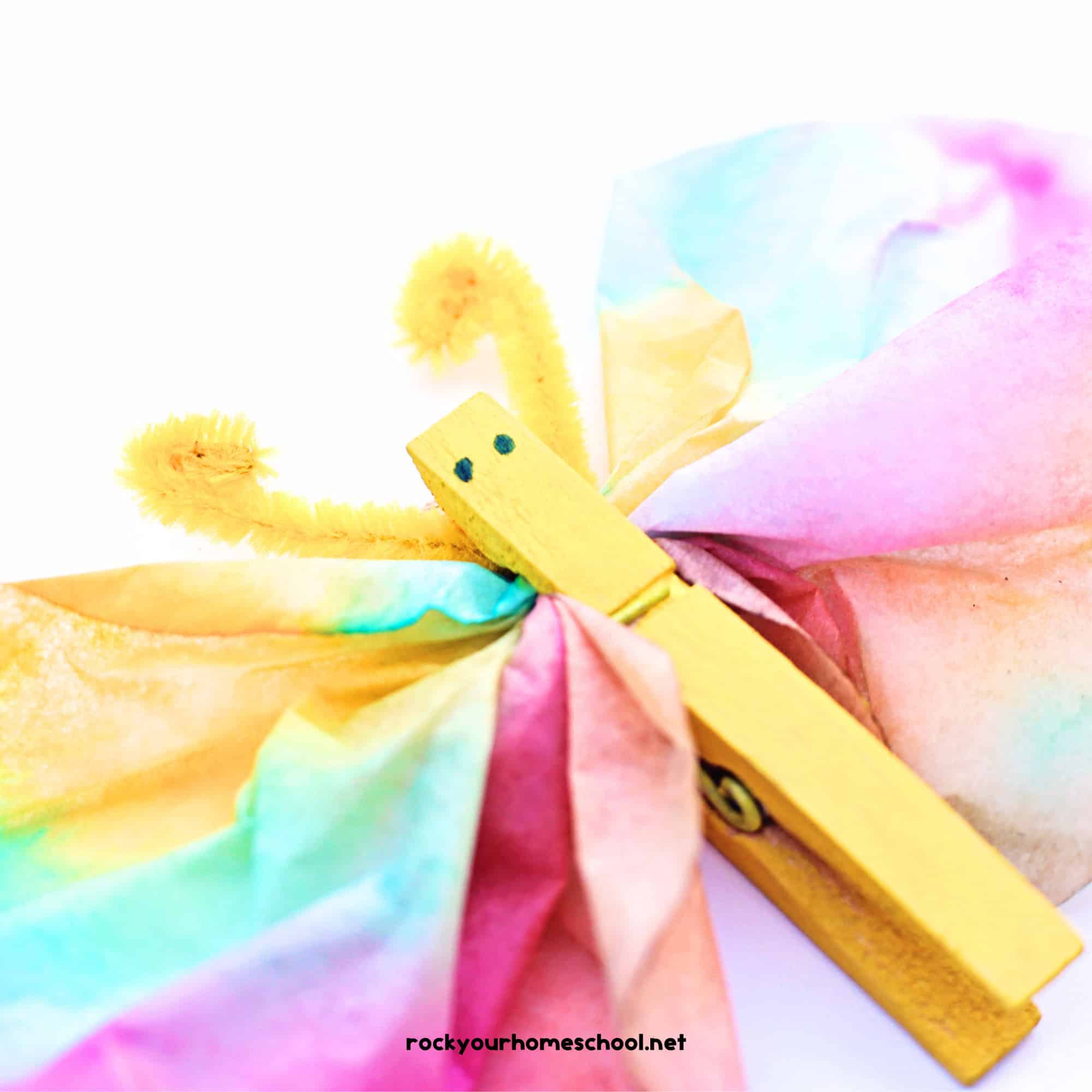 Yellow clothespin and pipe cleaner antenna on coffee filter butterfly craft.