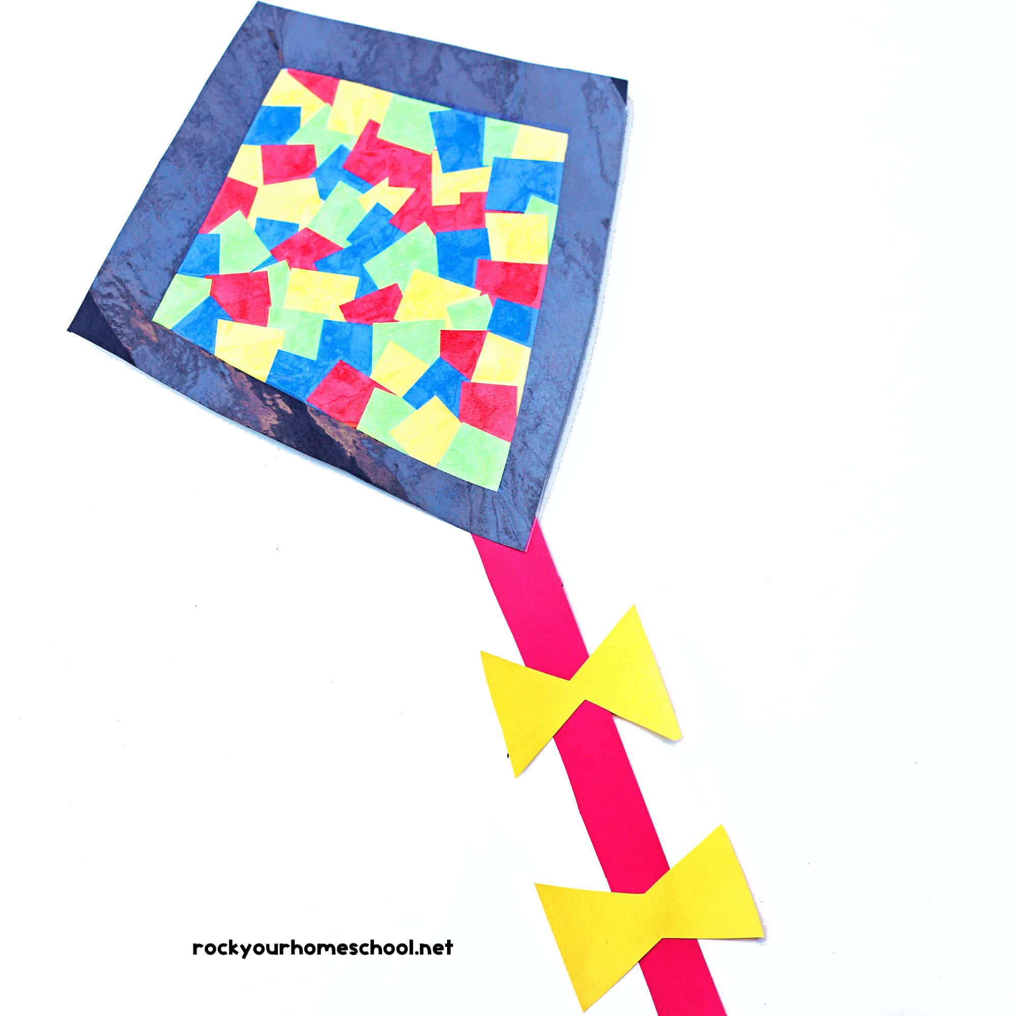 Colorful  suncatcher kite with contact paper, black diamond frame, red tail with yellow bows.