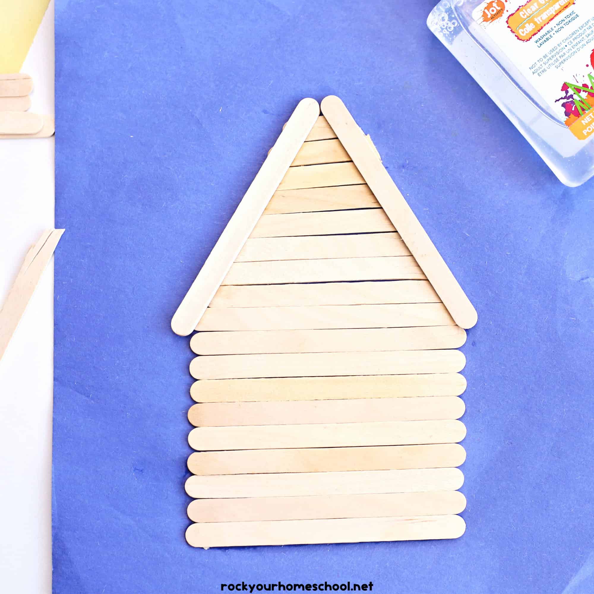 Popsicle sticks in shape of log cabin with clear glue.