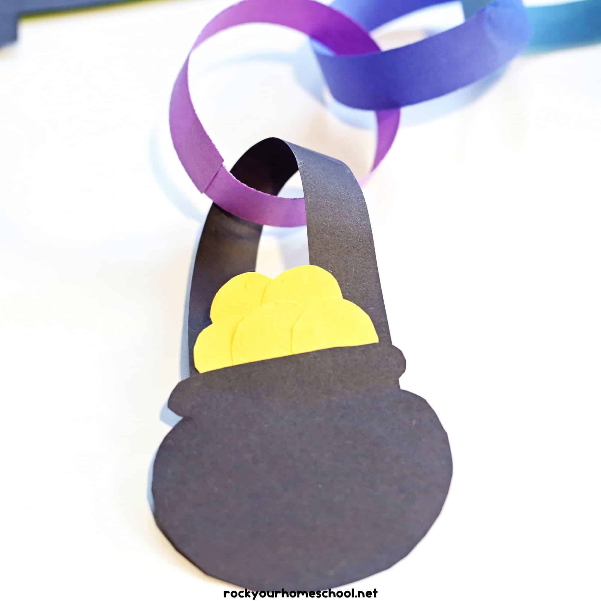 Black paper pot with gold coins linked to purple paper strip.