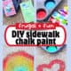 Muffin tray with water in jar, cornstarch box, gel food coloring box and green paint brush with heart, flower, and rainbow painted on sidewalk.