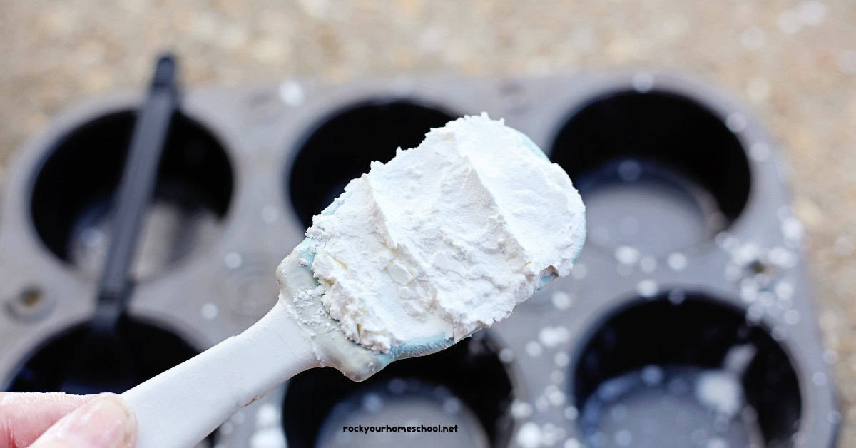 Woman holding tablespoon of corn starch over muffin tray.