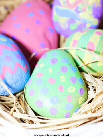 Basket with straw with Easter egg painted rocks.