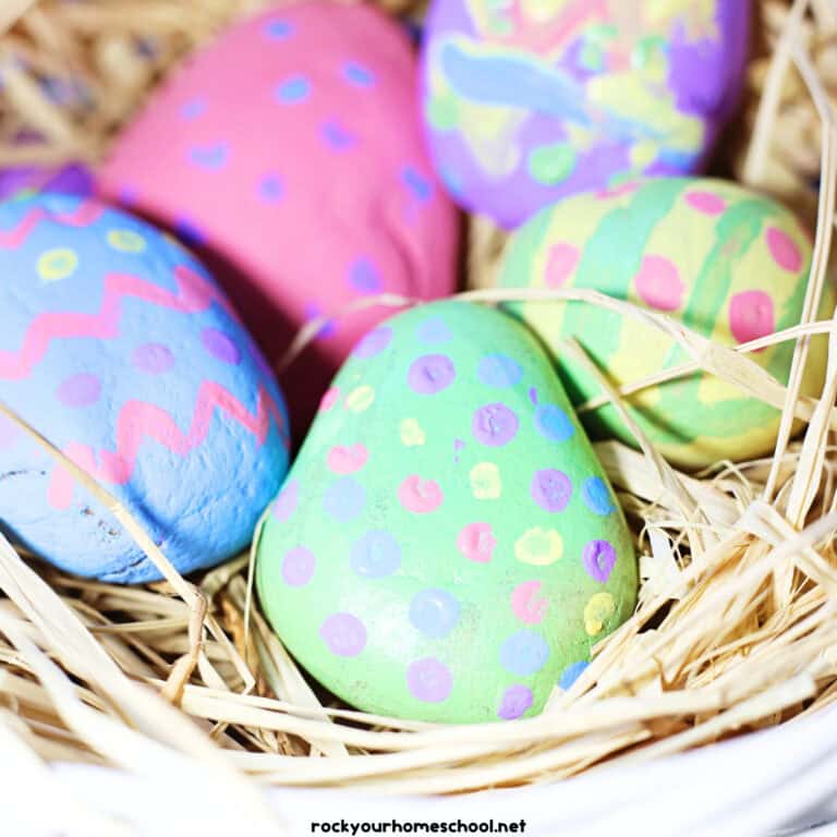 Basket with straw with Easter egg painted rocks.