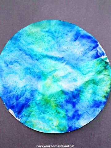 Example of blue and green coffee filter Earth craft on black paper.