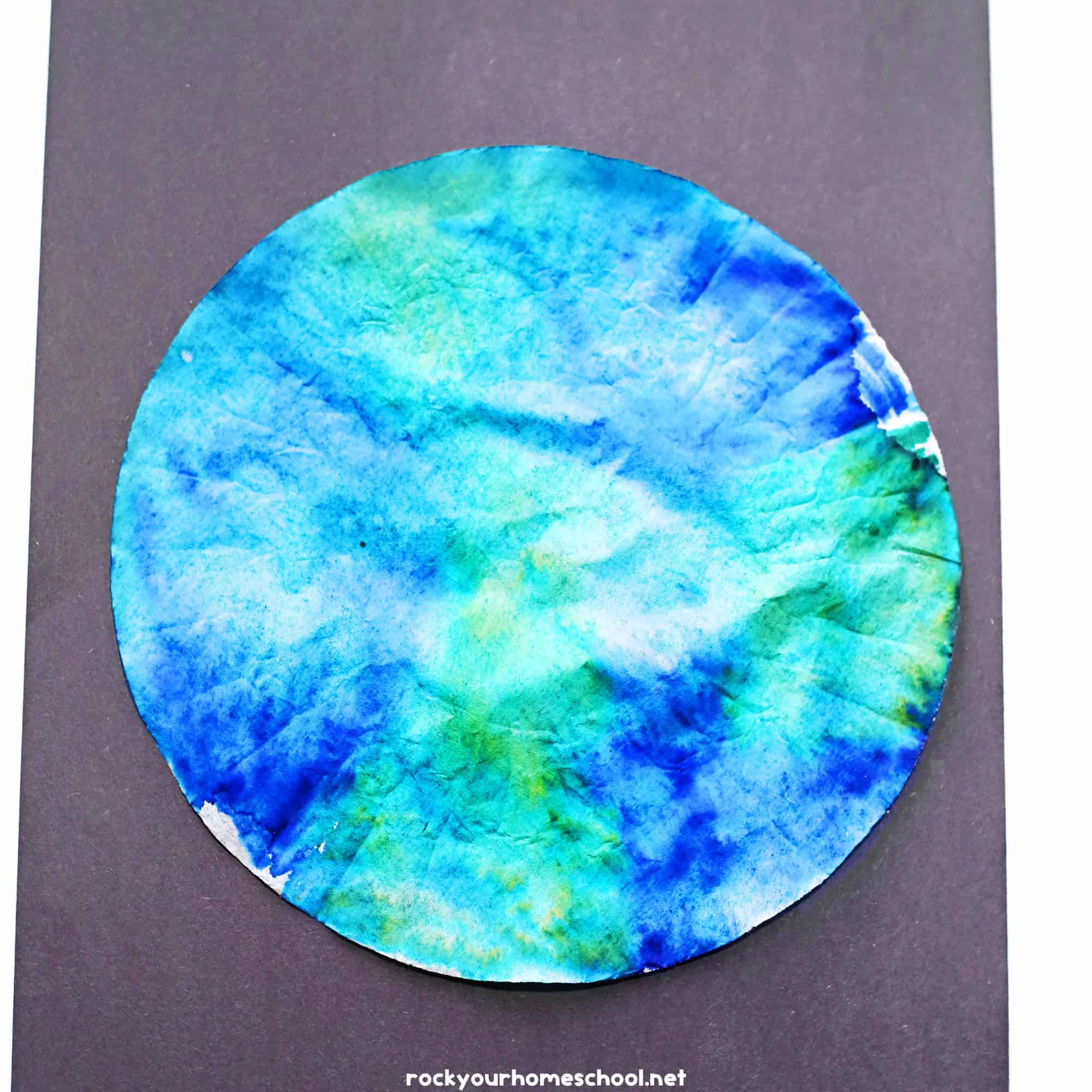 Example of blue and green coffee filter Earth craft on black paper.