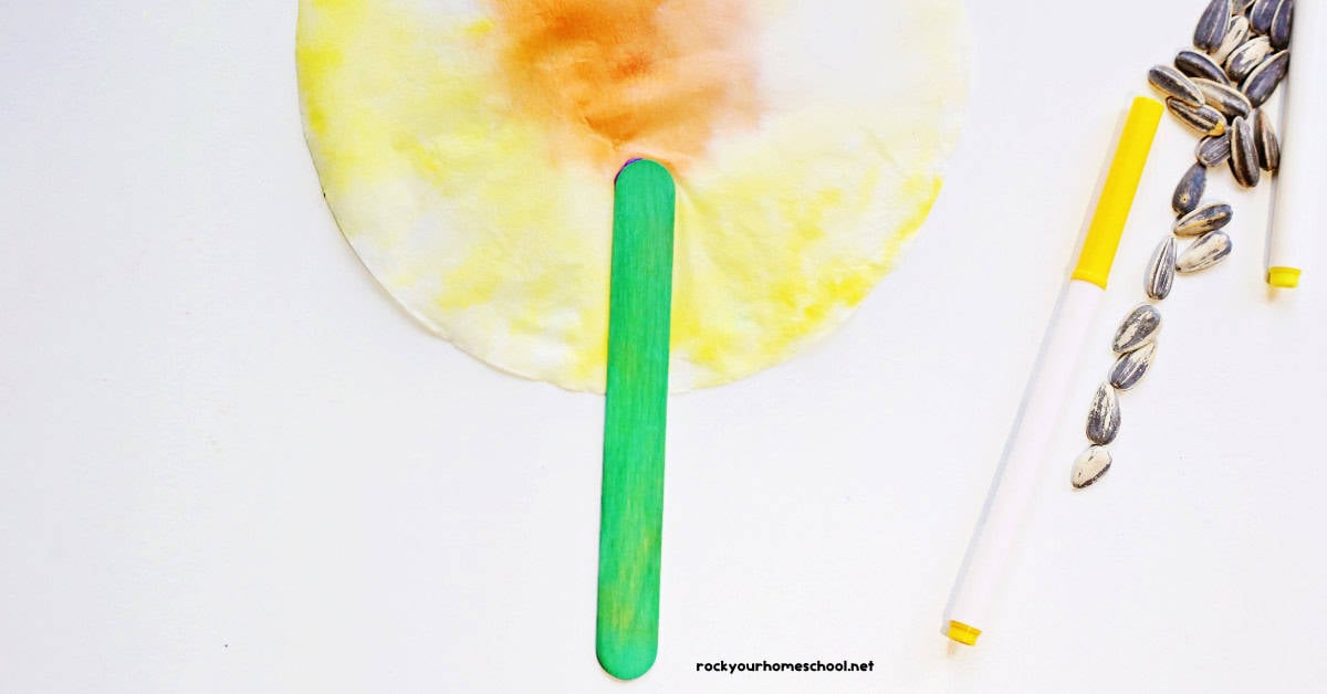 Green popsicle stick glued to back of yellow coffee filter.