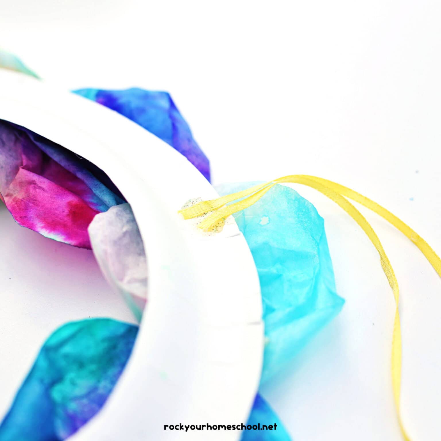 Yellow ribbon loop on back of paper plate frame with coffee filter flowers.