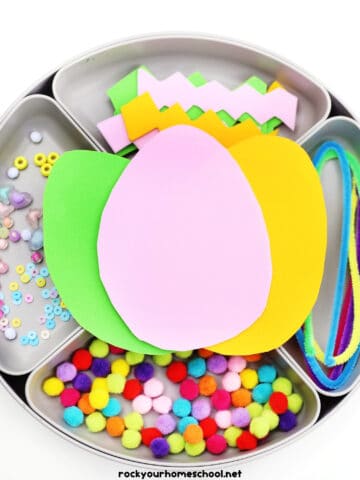 Activity tray with egg foam sheets, pipe cleaners, pom poms, beads, and other decorations.