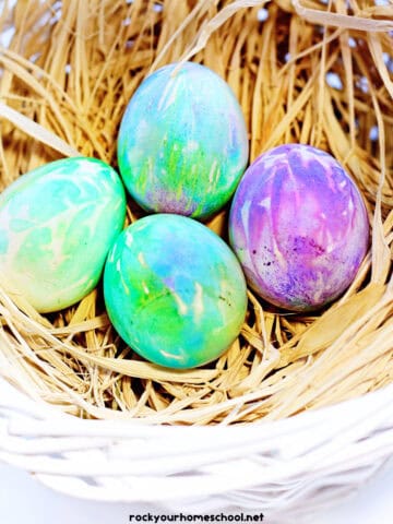 Examples of tie-dye Easter eggs in basket with straw.