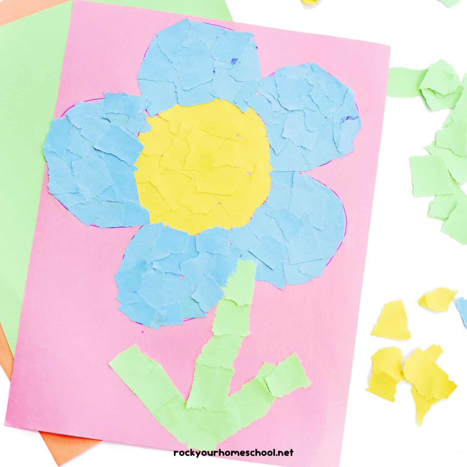 Example of torn paper flowers craft with light blue, yellow, and green on pink paper.