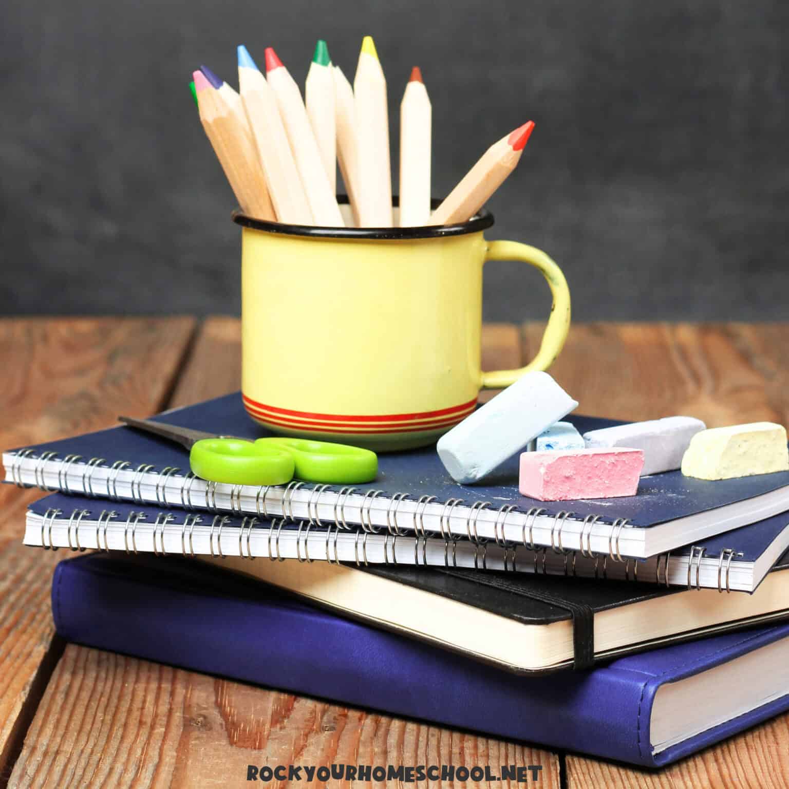 Books with yellow mug of color pencils and chalk to feature these April Homeschool Ideas.