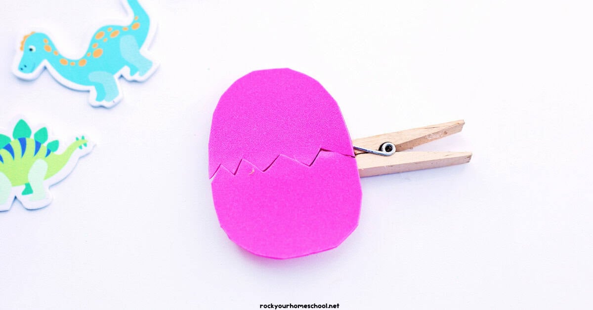 Pink foam sheet egg on clothespin wiht dinosaur stickers.
