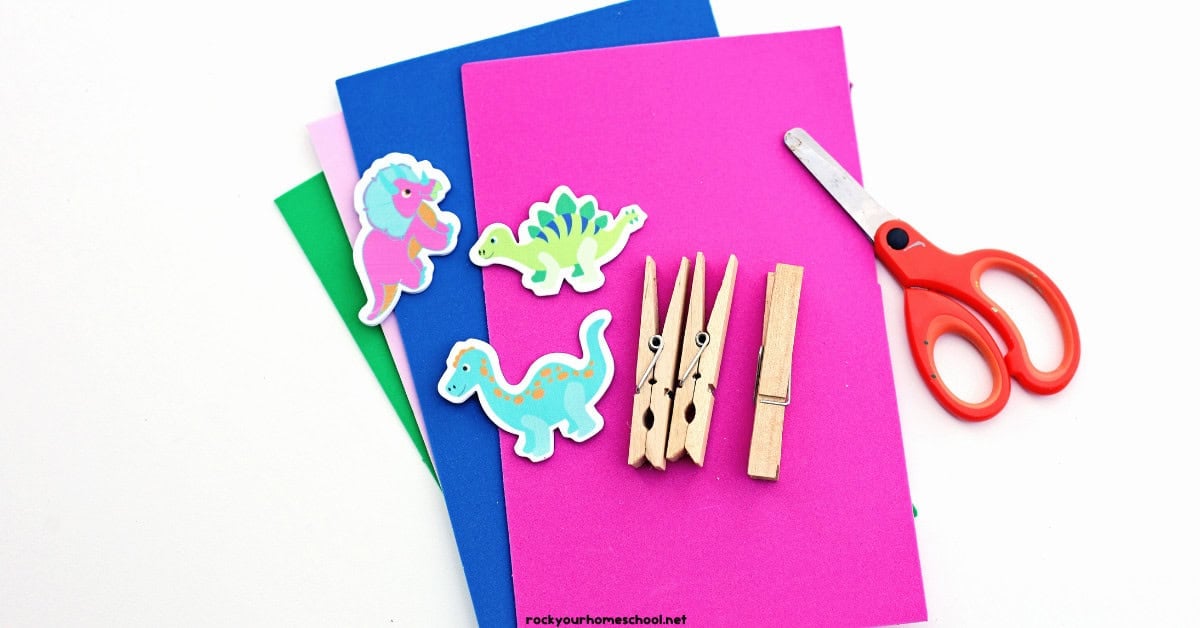 Foam sheets with scissors, clothespins, and dinosaur stickers.