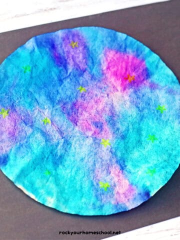 Example of galaxy craft for kids made with coffee filters and markers on black construction paper.