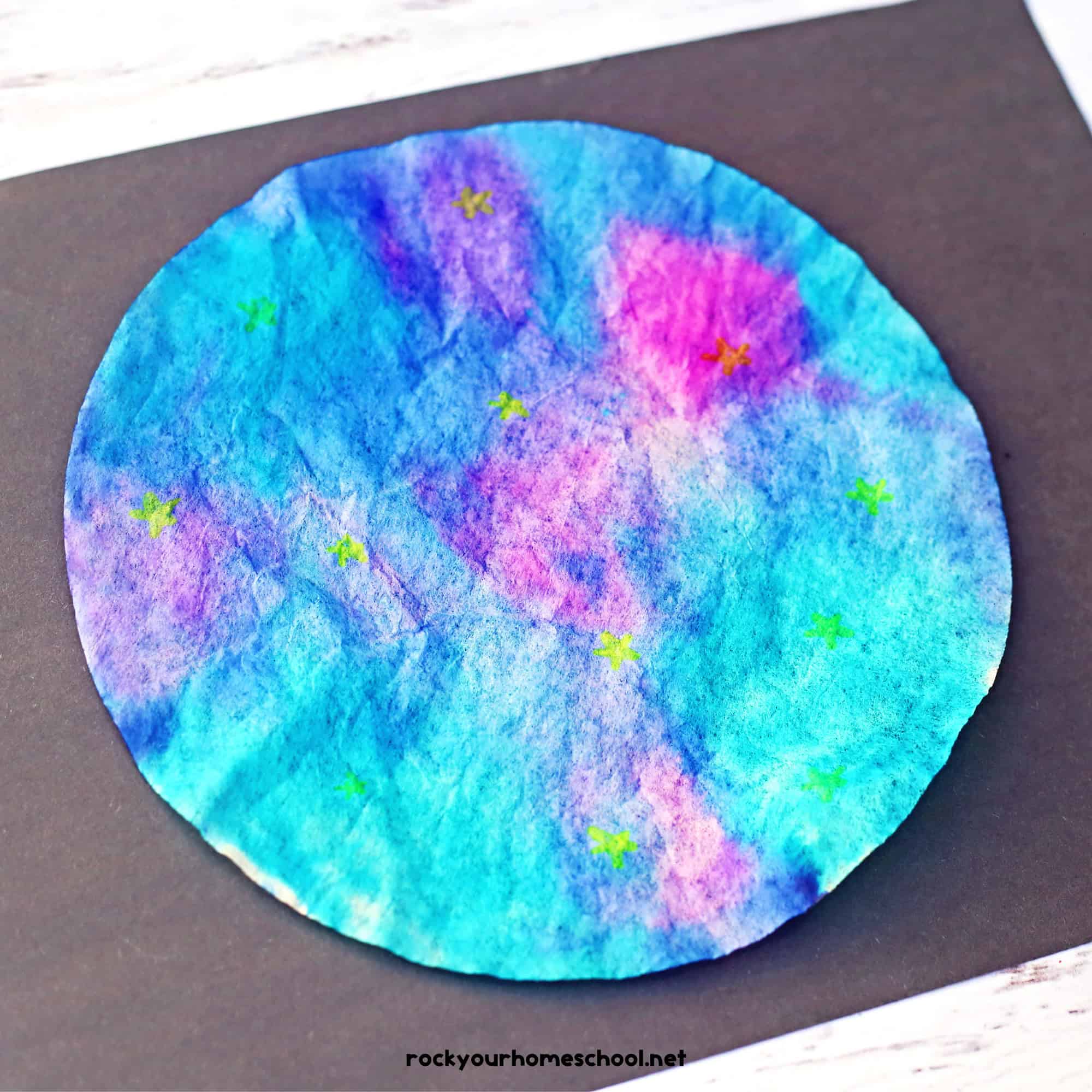 Example of galaxy craft for kids made with coffee filters and markers on black construction paper.