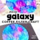 Person spraying water on colored coffee filter with example of coffee filter galaxy craft on black construction paper.