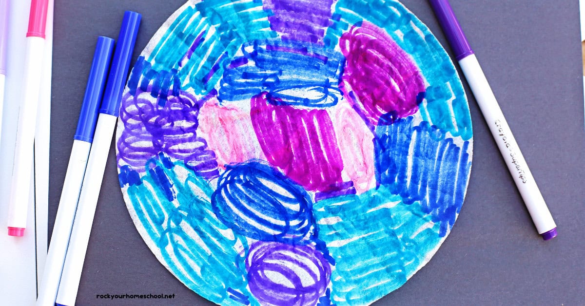 Coffee filter colored with pink, blues, and purple markers on black construction paper.