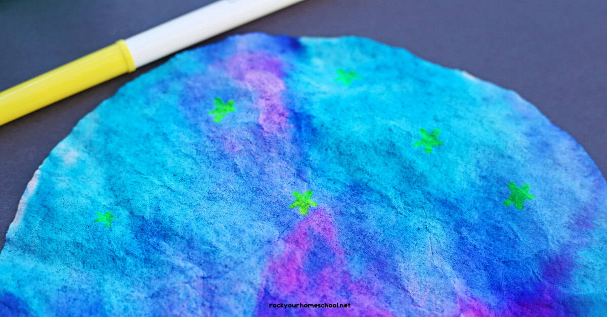 Coffee filter galaxy craft with neon yellow markers on black construction paper.