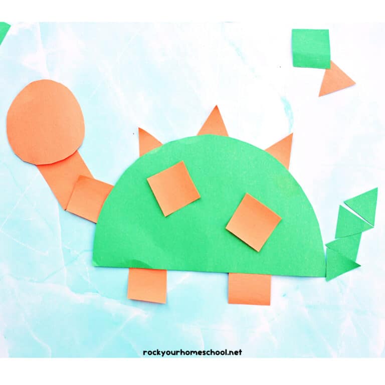 Example of orange and green easy paper dinosaur craft made with basic shapes like squares, circles, and triangles.