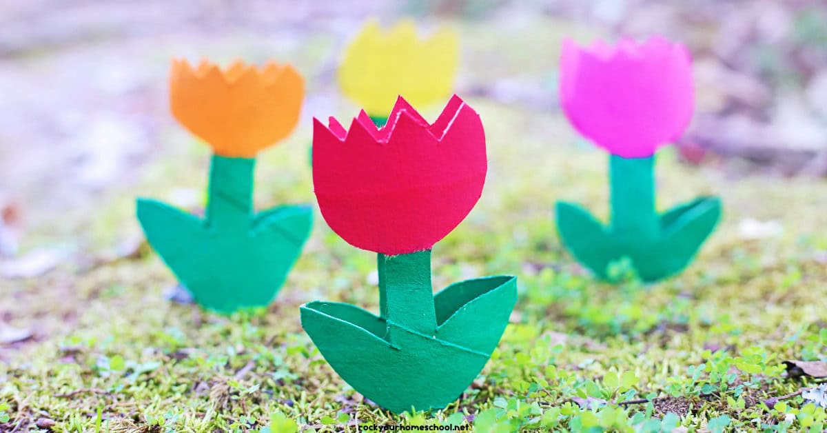 Examples of toilet paper roll tulips in red, orange, yellow, and pink on grass.