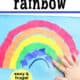 Child adding torn piece of blue paper to torn paper rainbow craft.