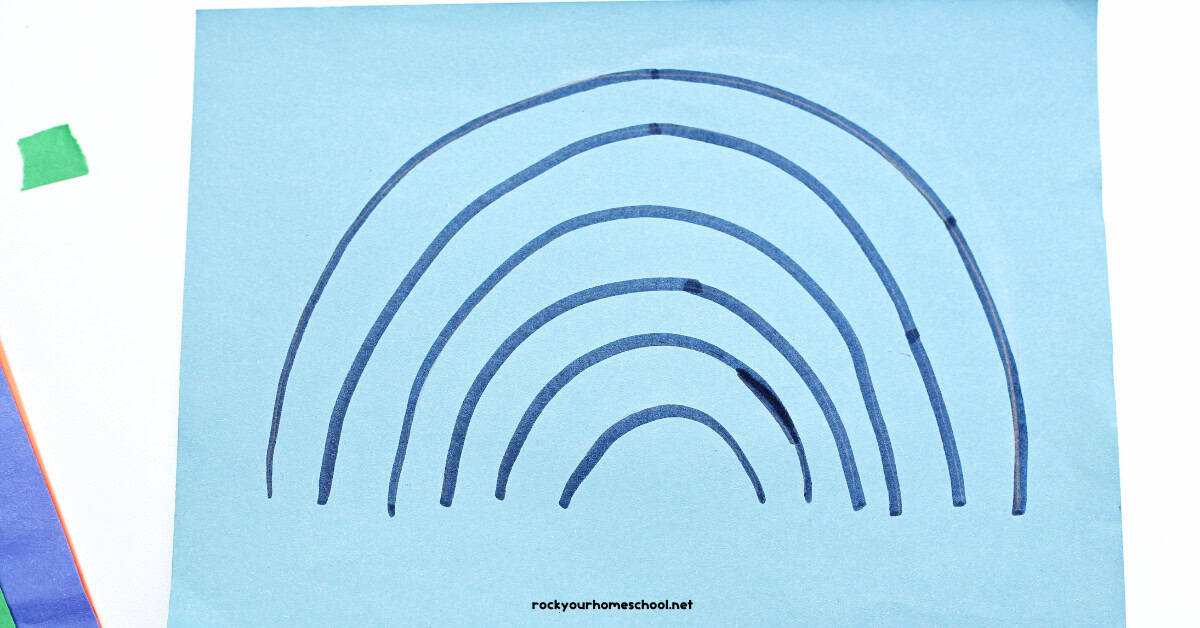 Rainbow shape drawn on light blue construction paper.