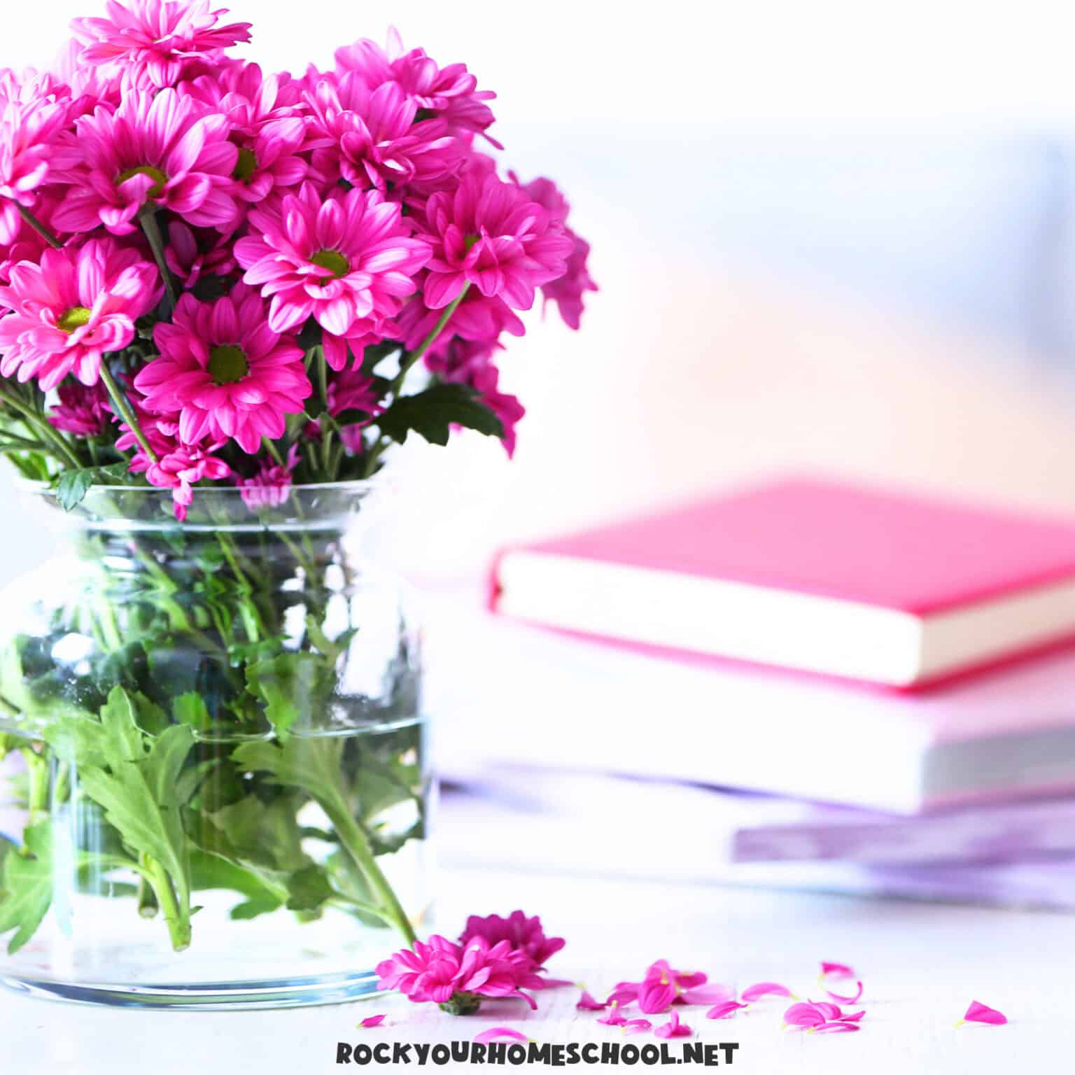 May homeschool ideas with books and pink flowers in glass vase.